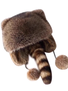 Detail of winter raccoon style faux fur hat with striped tail and earmuffs for cold weather