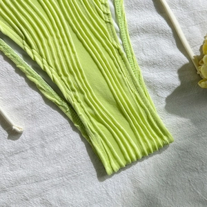 Macro detail of lime green ribbed bikini fabric with white drawstring and double stitching