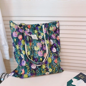 Detail of green floral canvas tote bag showing the artistic pattern and white woven label