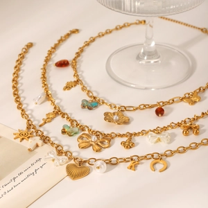Colliers en acier doré avec pendentifs papillon, cœur et fleur sur un fond beige élégant