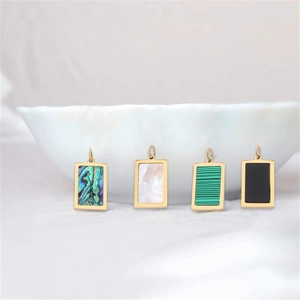 Detailed macro view of rectangular 18k gold pendants inlaid with natural abalone shell