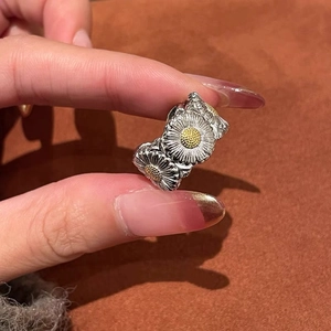 Detail of silver daisy ring featuring delicate yellow florets and embossed floral pattern