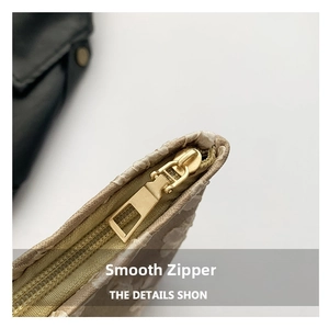 Detail of smooth gold zipper and embossed floral texture on beige handbag fabric