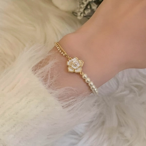 Elegant Camellia flower pearl bracelet with gold chain and crystals on a white fur background