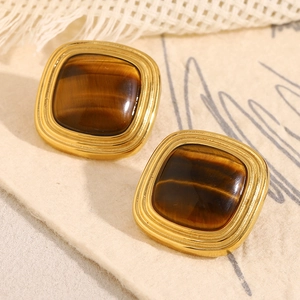 Macro shot of gold-plated square earrings featuring natural brown tiger eye stone inlay