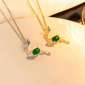 Detailed view of silver and gold reindeer necklaces with emerald green stones