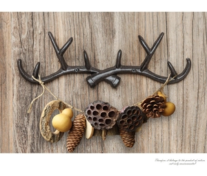 Close-up of vintage antler wall hook in dark cast iron finish on a rustic wood wall