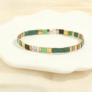 Detailed view of colorful Tila bead bracelets on a white ceramic shell tray decor