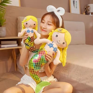 Close-up of soft mermaid plush toy with yellow hair and colorful scales in bedroom setting