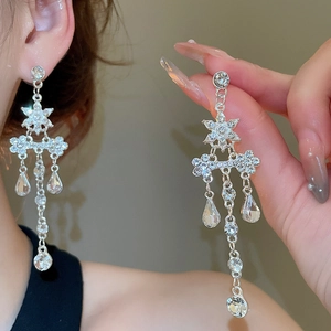 Détail des boucles d'oreilles argentées avec fleurs en cristal et longues pampilles