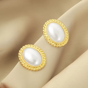Macro view of vintage gold stud earrings featuring textured edges and oval faux pearls