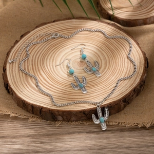 Detail of vintage silver cactus jewelry set with turquoise beads on a rustic wood base