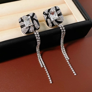 Close-up of square silver needle earrings with shimmering double row tassel rhinestones