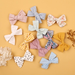 Detailed flat lay of assorted fabric bow hair clips in various patterns on yellow background