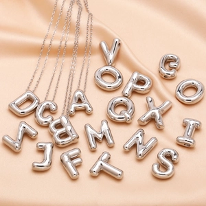3D balloon alphabet necklace in polished silver finish on champagne silk background