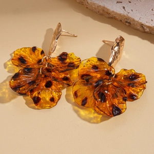 Detailed shot of amber acrylic petal earrings with golden metal stud on stone base
