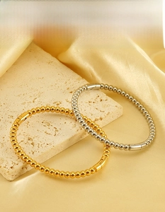 Detail of beaded stainless steel bracelets in gold and silver finish on silk