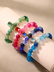 Detail of beaded elastic bracelets with square gold pendants and colorful gemstones