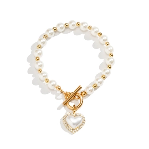 Detail of pearl beaded bracelet with gold accents, heart pendant and toggle clasp