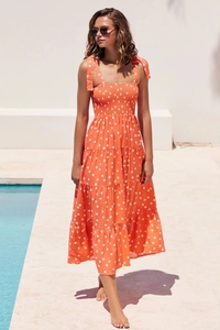 Détail de robe midi orange à pois avec ourlet à volants et bretelles à nouer