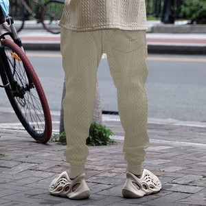 Detail of light khaki knitted joggers with a textured cable knit pattern and ribbed cuffs