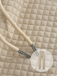 Macro detail of men's beige quilted jogger fabric with woven drawstring and metal tips