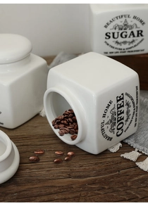 Detail of white ceramic coffee and sugar jars with lids on a rustic wooden table surface