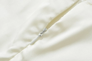 Detailansicht des nahtlosen Reißverschlusses am weißen Neckholder-Kleid aus Satin