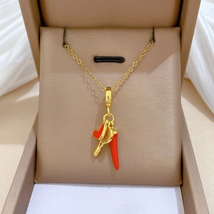 Close-up of gold chain necklace featuring red heart, tennis racket and horn charms