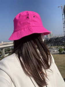 Detail shot of a neon rose red cotton bucket hat with metal ventilation eyelets and stitching