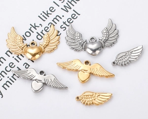 Macro detail of heart-shaped wing pendants in polished gold and silver stainless steel