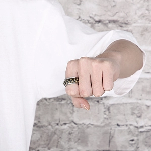 Detail of a punk style spinning ring featuring double row skull engravings on wide band