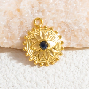 Macro detail of 18K gold evil eye charm with blue gemstone on textured white stone