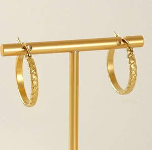 Detail of 18K gold titanium steel hoop earrings with woven texture on a T-stand