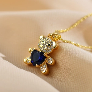 Detailed macro shot of golden bear pendant with heart blue stone on satin fabric