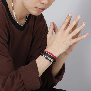 Close-up of a model wearing a multi-layer red and black braided leather bracelet with clasp