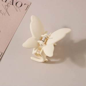 Vue détaillée d'une pince à cheveux papillon en finition beige mat avec ressort métallique