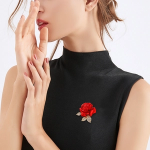 Elegant red rose brooch with metal leaves and crystals on a professional model
