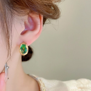 Detail of vintage French gold-plated earrings with irregular hammered texture and green opal