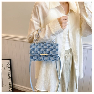 Détail du sac en denim à damier bleu avec bords effilochés et boucle en métal doré