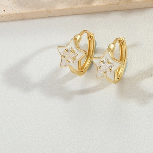 Close-up of gold star hoop earring with white enamel and sparkling center zircon stone