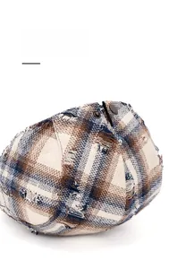 Détail de la boucle métallique réglable sur béret vintage à carreaux à bords usés