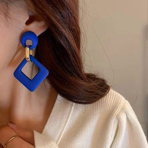 Detail of geometric blue drop earrings featuring circular and diamond-shaped resin parts
