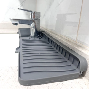 Close-up of grey silicone faucet splash pad with drainage grooves on a stone countertop