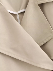 Dettaglio macro del bavero del trench kaki che mostra la trama del tessuto in twill pregiato