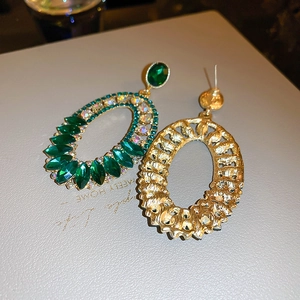 Detailed view of oval vintage earrings with green gemstones and sparkling crystals