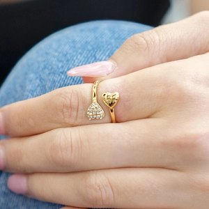 Detalle de anillo ajustable de doble corazón en oro llevado sobre fondo de mezclilla