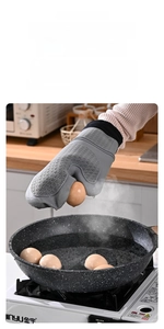 Close-up of heat-resistant silicone glove lifting a boiled egg from bubbling hot water