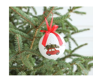 Close-up of a white Christmas foam ball with red truck print hanging on a festive tree
