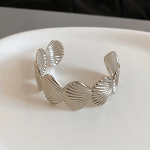 Detailed macro view of silver shell-shaped cuff bracelet with fine vertical textured stripes